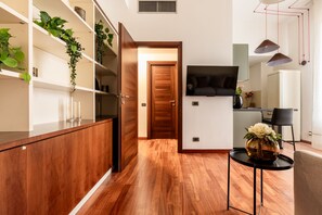 A modern kitchen with wooden cabinets, a built-in stove, and a dining area with a table and chairs. - Garibaldi - Bright Cozy 1 BR in the Heart of Brera (Milan)
