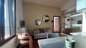Una sala de estar moderna con un sofá, un sillón curvo, una mesa de centro y un televisor.