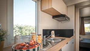 Uma cozinha compacta com bancada de madeira, pia e janela com vista para o verde.