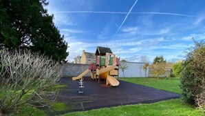 Un'area giochi con uno scivolo e strutture per arrampicarsi, immersa nel verde dell'erba e degli alberi.