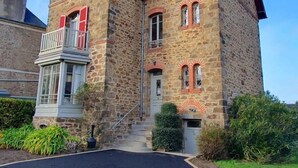 Un edificio in pietra con un balcone, un piccolo giardino e cielo sereno.