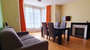 Una sala de estar con sofá, mesa de comedor, sillas y chimenea.