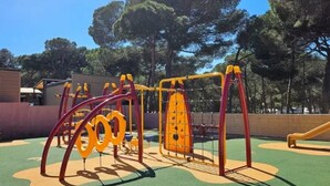 Ein Spielplatz mit verschiedenen Spielgeräten, darunter Schaukeln, Rutschen und Kletterbereichen.