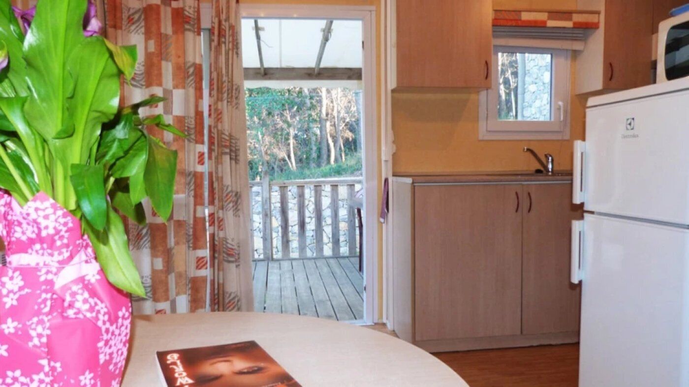 A compact kitchen with wooden cabinets, a built-in microwave, and a window above the sink.