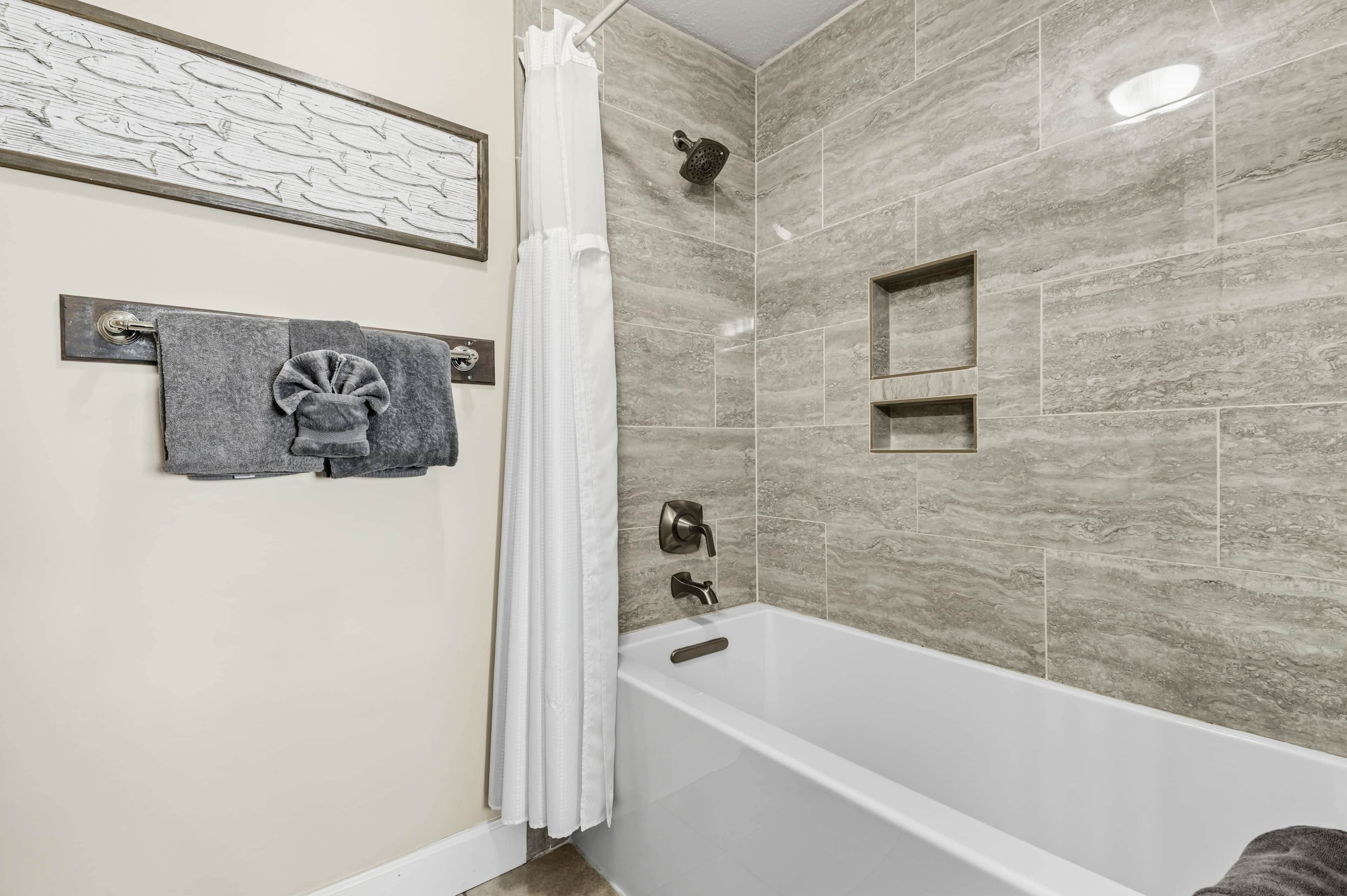 Ein Badezimmer mit Badewanne, Dusche und einem Handtuchhalter mit Handtuch.