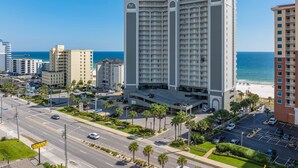 Een meerlaags hotel met een binnentuin, een parkeergarage en uitzicht op het strand.