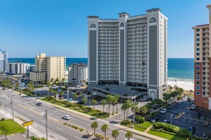 A multi-story hotel with a central courtyard, a parking garage, and a view of the beach. - 1704 Seawind w Free Umbrella Svc Double Balcony (Gulf Shores)