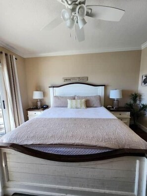A neatly made bed with a headboard, two bedside lamps, a ceiling fan, and a window with curtains. - 1704 Seawind w Free Umbrella Svc Double Balcony (Gulf Shores)