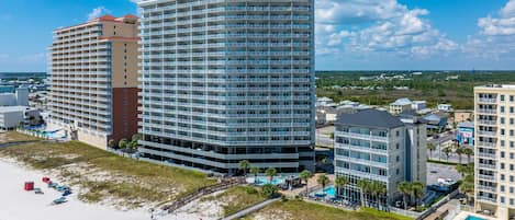 Un hôtel situé en bord de mer, avec plusieurs étages, une piscine et un espace de plage.