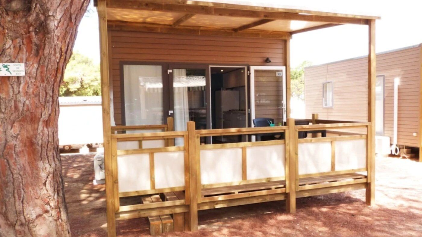 Une structure en bois dotée d’un porche couvert, d’une porte-fenêtre coulissante et d’une petite table.