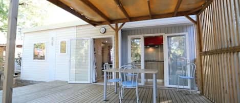A covered patio with a table and chairs, a sliding glass door, and a wooden fence.