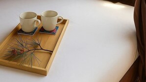 Una carpa con una cama, dos tazas blancas sobre una bandeja y una ventana con cortinas.