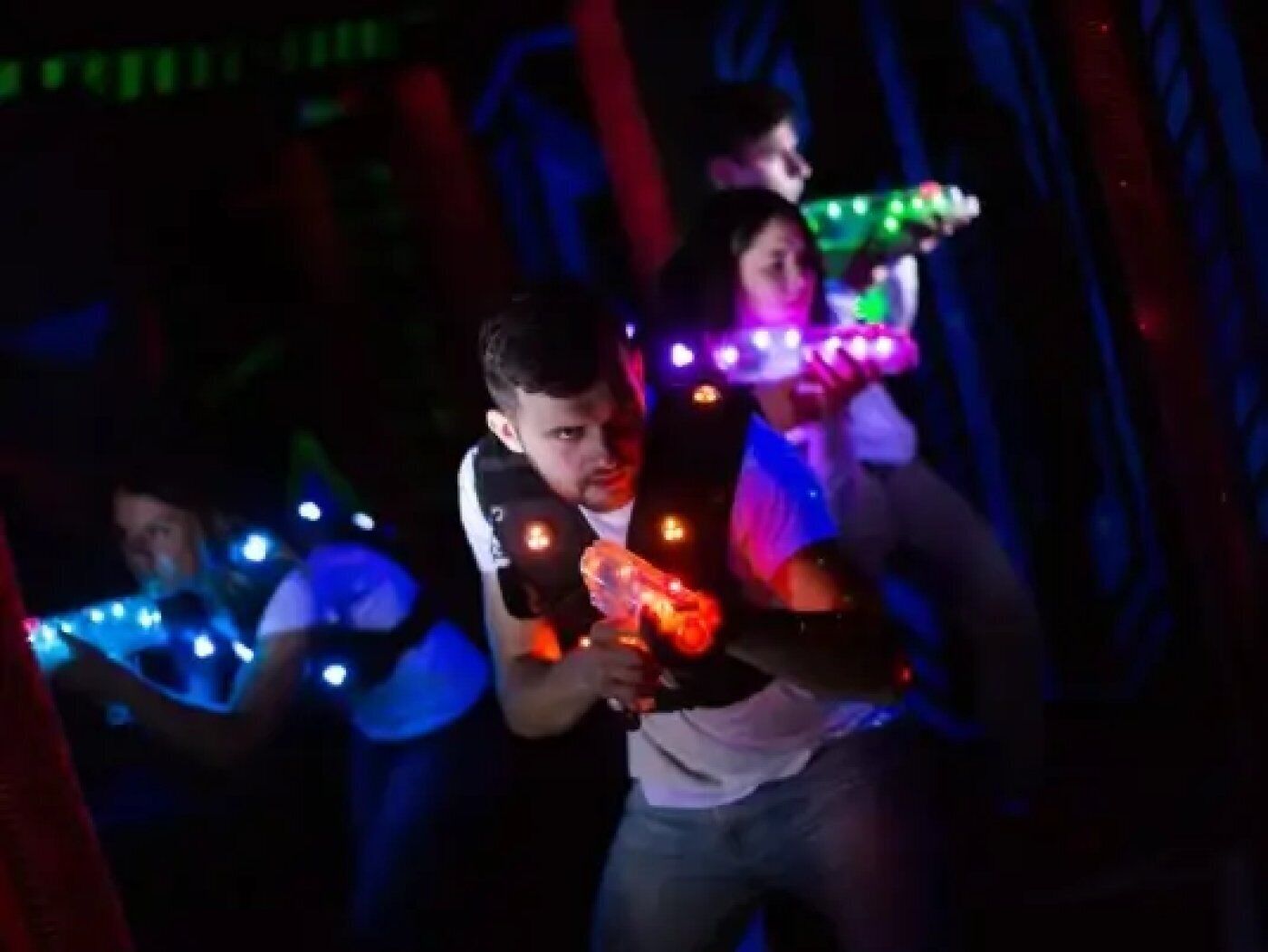 Um grupo de pessoas segurando gravetos luminosos em um quarto escuro.