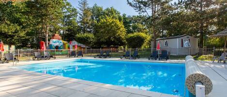 A swimming pool with lounge chairs and a thatched umbrella.