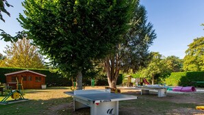 Un parque con mesa de ping pong, juegos infantiles y una cabaña de madera.
