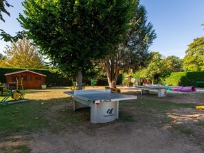 Ein Park mit einem Tischtennisplatte, Spielgeräten und einer Holzhütte.