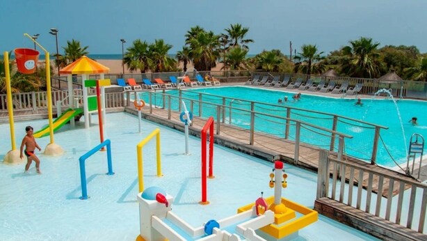 A pool area with a slide, water play structures, and lounge chairs. - ZEcamping 4* piscine chauffée pet friendly mobil-home TV BBQ clim 31m2 (Portiragnes)