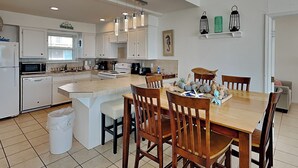Una cocina moderna con armarios blancos, una isla central y sillas de madera.