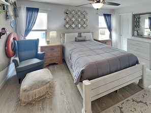 A bedroom with a bed, a chair, a nightstand, a lamp, and a ceiling fan. - Allegro North #406 | Bayfront Condo w/Great Views & Private Balcony (Rockport)