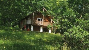 Une cabane en bois dotée d’un balcon, entourée d’une végétation luxuriante.