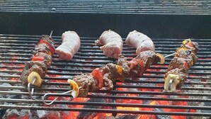 Un barbecue avec des brochettes de viande et de légumes en train de cuire au charbon de bois.