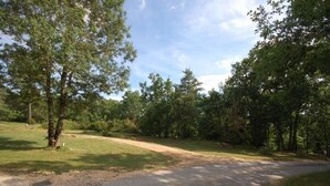 Une route asphaltée qui mène à une zone boisée, avec des arbres et de l’herbe.