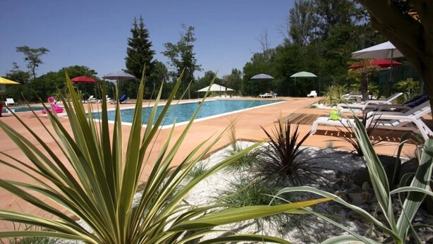 A pool area with lounge chairs and umbrellas, surrounded by greenery. - ZEcamping 3*chiens acceptés piscine en bord de rivière avec Canoë (Mazères)