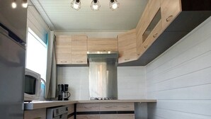 A compact kitchen with wooden cabinets, a stainless steel range hood, and a built-in microwave.