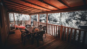 Une terrasse en bois avec une table et des chaises, donnant sur une zone boisée.