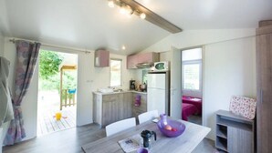 Une cuisine moderne avec un coin repas, une petite table sur laquelle se trouve un bol violet et une machine à café, et une vue sur l’extérieur.