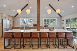 A modern kitchen with a central island, bar stools, and large windows. - Rider's Retreat- Silas Jayne's renovated farmhouse overlooking Our Day Farm (Elgin)