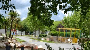 Eine Wohnstraße mit Häusern, einem Spielplatz und Grünflächen.