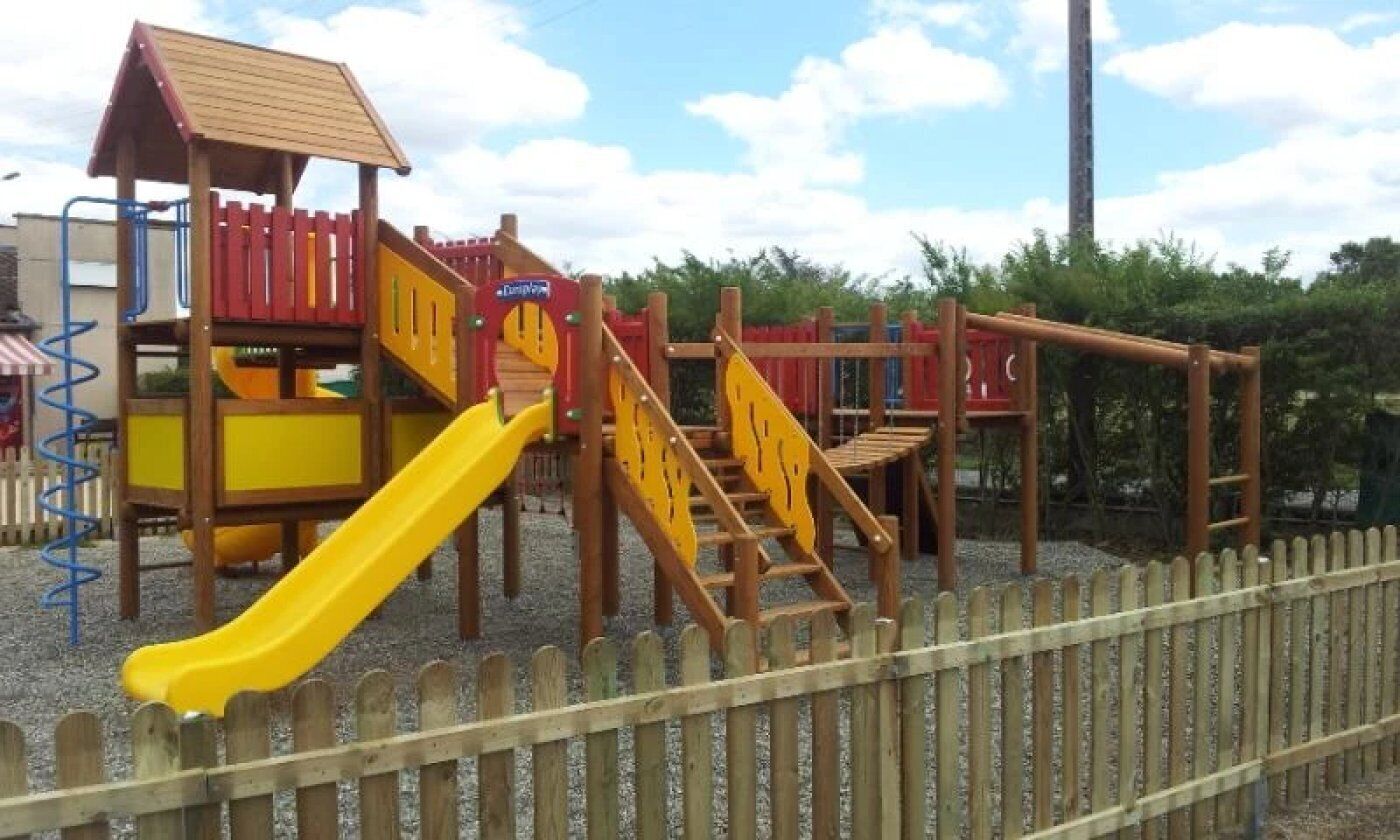 A playground with a slide, climbing structures, and a fenced area.