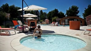 A swimming pool area with lounge chairs, umbrellas, and a small building structure.