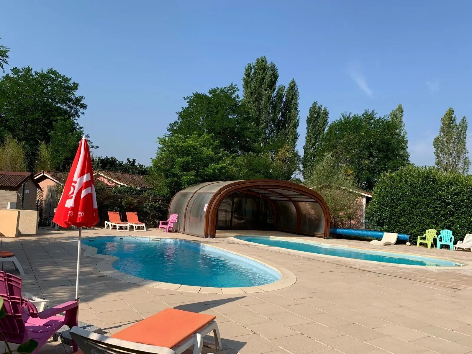 A swimming pool with lounge chairs and a covered seating area.