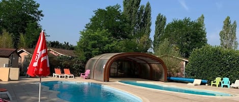 A swimming pool with lounge chairs and a covered seating area.
