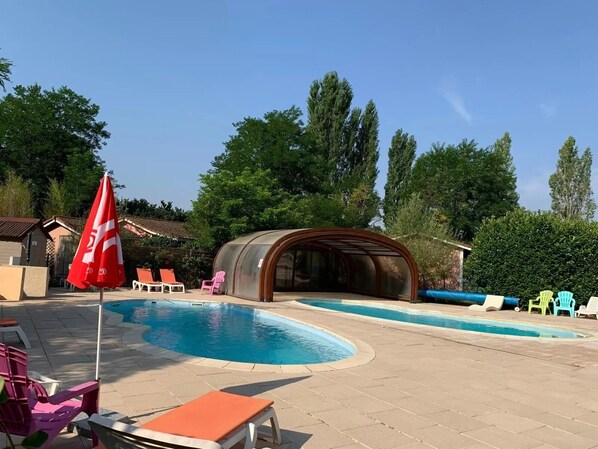 Une piscine avec des chaises longues et un espace de repos abrité.