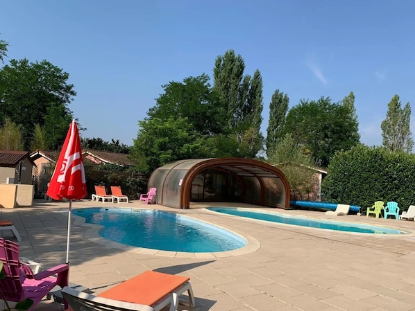 A swimming pool with lounge chairs and a covered seating area.