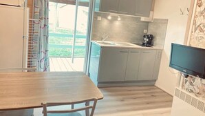 Cocina compacta con comedor, televisor y vista al exterior.
