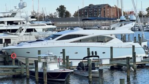 Een jachthaven met verschillende jachten die aanmeren, houten pijlers en een gebouw op de achtergrond.