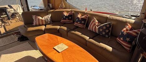 A boat interior with a sofa set and a wooden table, featuring American flag pillows.