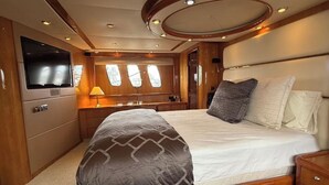 Een ruime slaapkamer met een groot bed, een televisie en een raam met uitzicht.