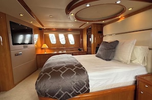 A spacious bedroom with a large bed, a television, and a window with a view.