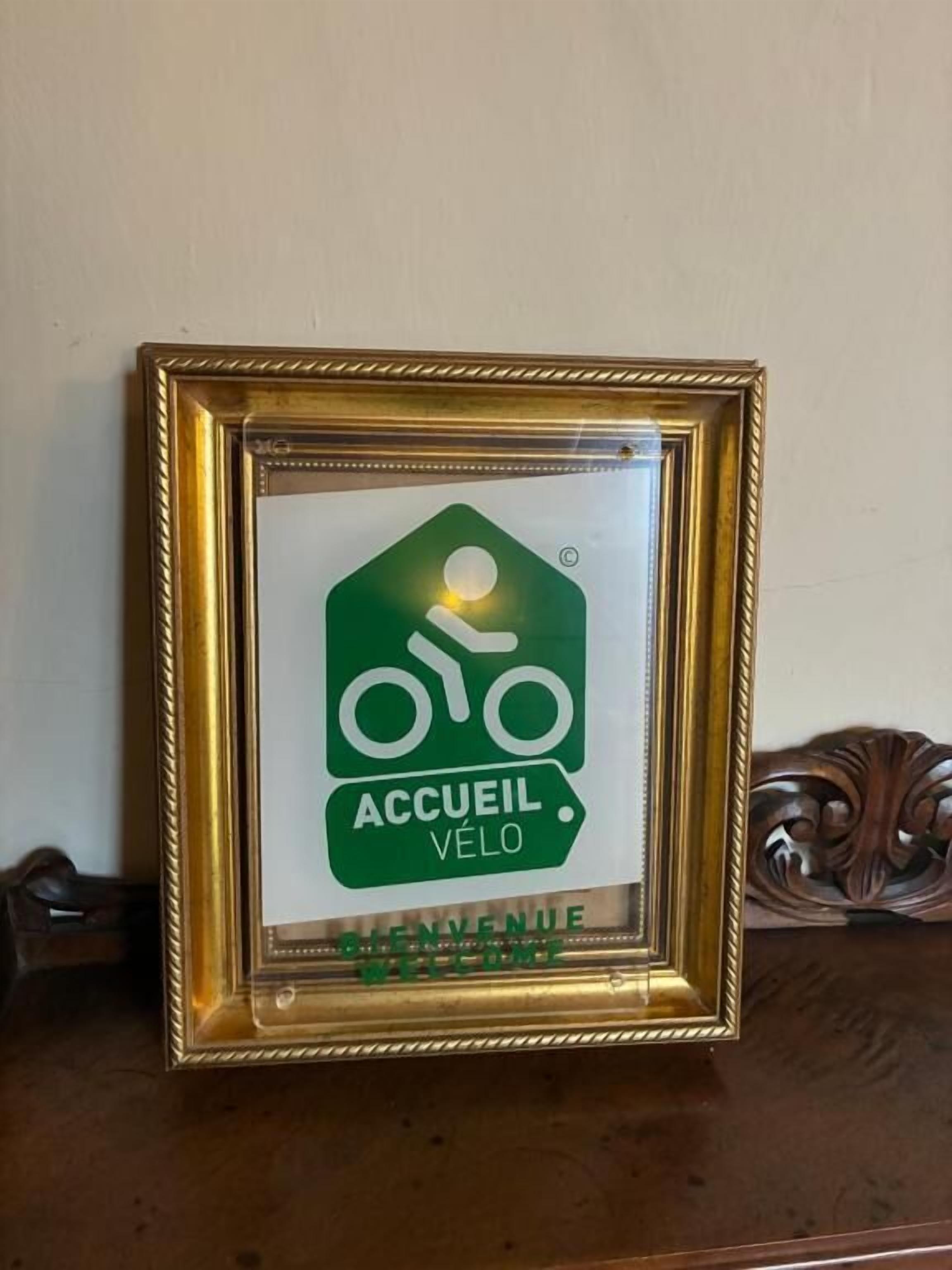 A framed welcome sign with a bicycle symbol and the text "ACCUEL VÉLO" indicating a bicycle-friendly accommodation.