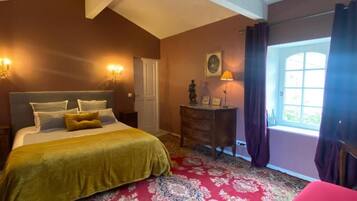 Un dormitorio con cama, cómoda, lámpara, ventana con cortinas y puerta.