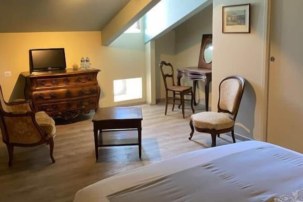 Ein Schlafzimmer mit Bett, Schminktisch, Fernseher und Sitzecke.