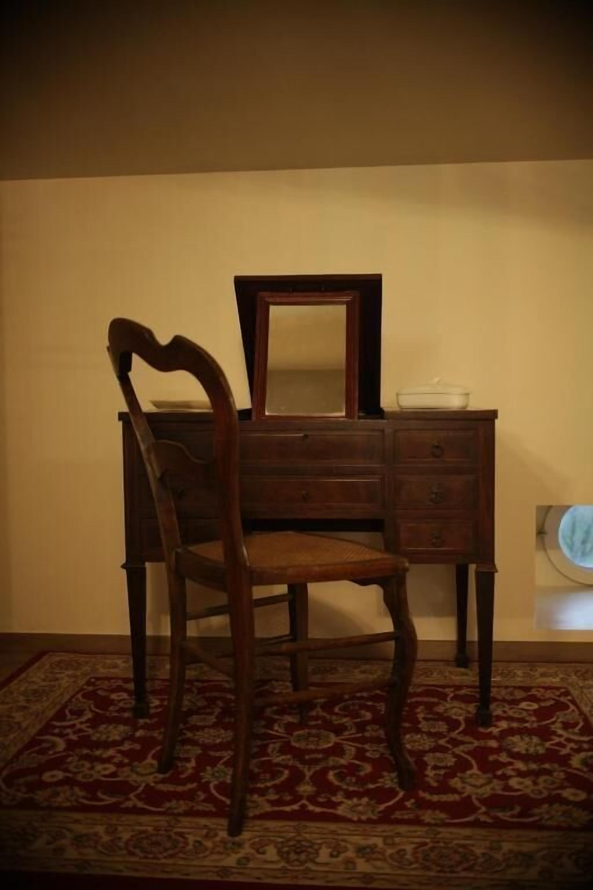 Une commode en bois, dotée d’un miroir et de tiroirs, posée sur un tapis à motifs.