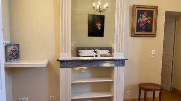 A room with a white console table, a chandelier, and two framed floral paintings on the walls.