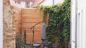Eine Terrassenfläche mit Holzzaun, Gartenmöbeln und Kübelpflanzen.