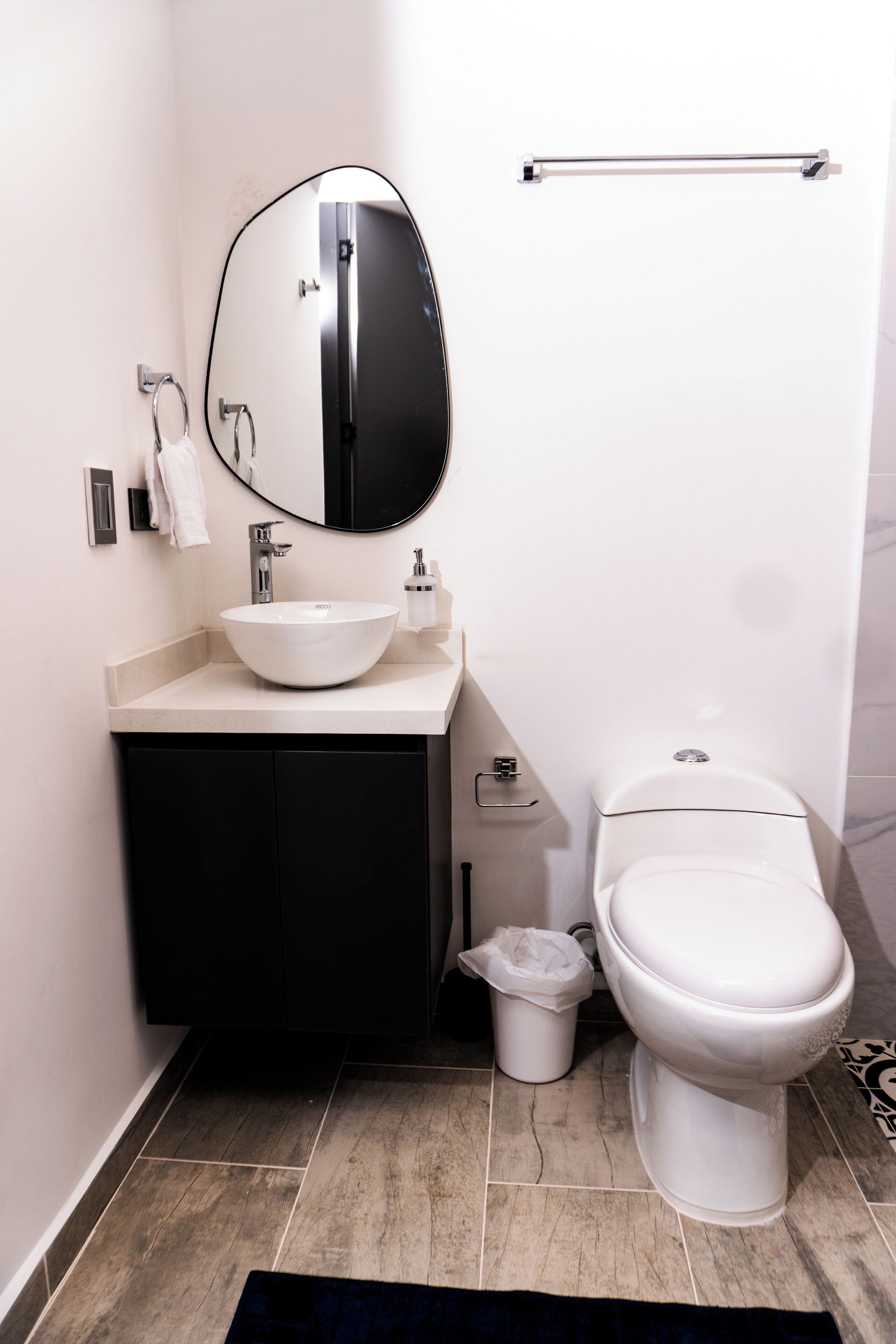 A modern bathroom with a white sink, black cabinet, and a toilet.
